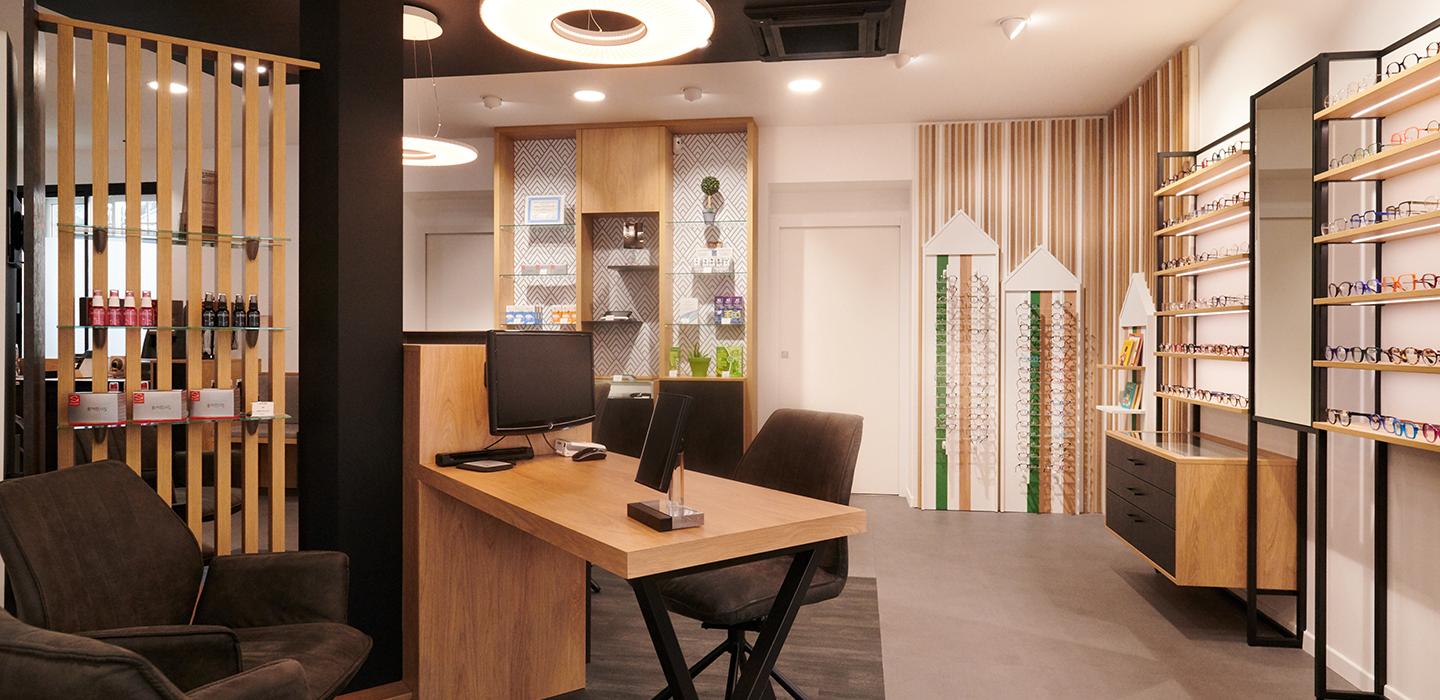 Repenser son agencement en diminuant son exposition tout en la mettant plus en valeur Et profiter de son extension pour accueillir au mieux ses clients Des mobiliers sur mesure bois/métal avec éclairage intégré Une salle d’examen de vue Un atelier ouvert sur l’espace de vente Un ilot de table de vente facilitant la circulation périphérique
