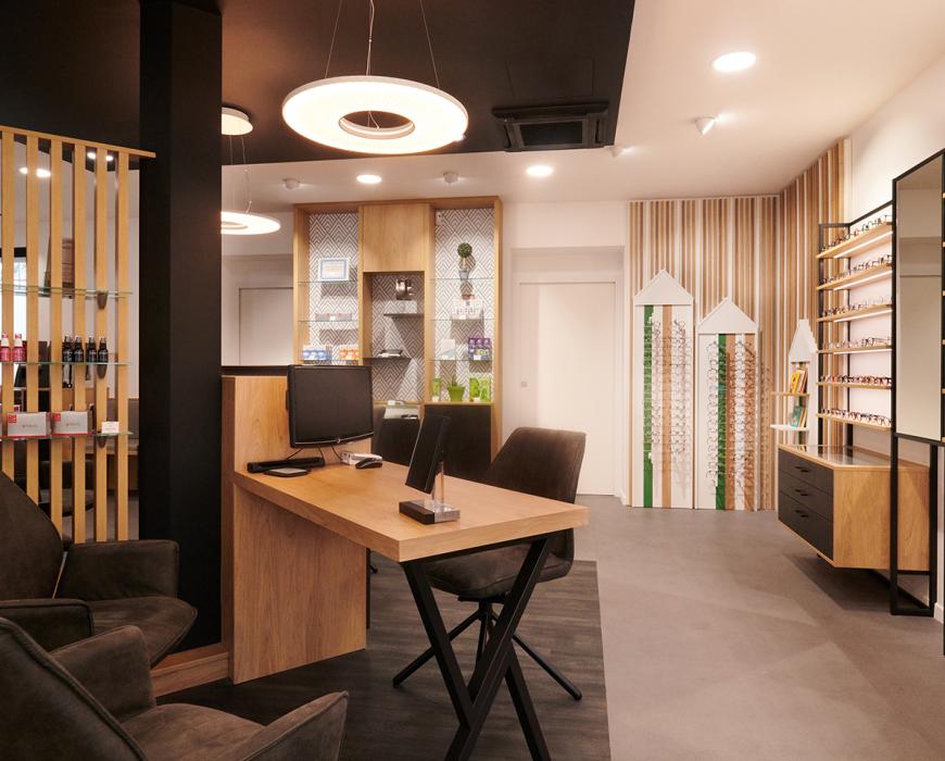 Repenser son agencement en diminuant son exposition tout en la mettant plus en valeur Et profiter de son extension pour accueillir au mieux ses clients Des mobiliers sur mesure bois/métal avec éclairage intégré Une salle d’examen de vue Un atelier ouvert sur l’espace de vente Un ilot de table de vente facilitant la circulation périphérique