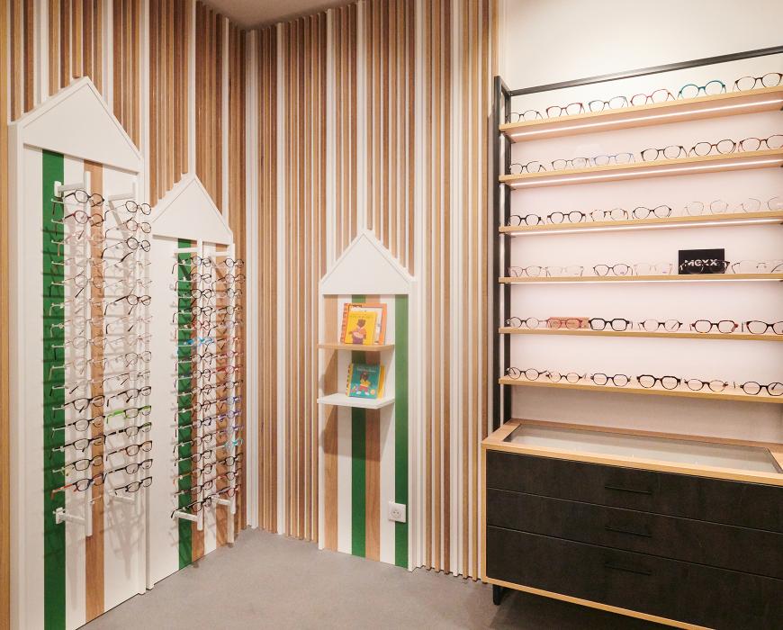 Repenser son agencement en diminuant son exposition tout en la mettant plus en valeur Et profiter de son extension pour accueillir au mieux ses clients Des mobiliers sur mesure bois/métal avec éclairage intégré Une salle d’examen de vue Un atelier ouvert sur l’espace de vente Un ilot de table de vente facilitant la circulation périphérique