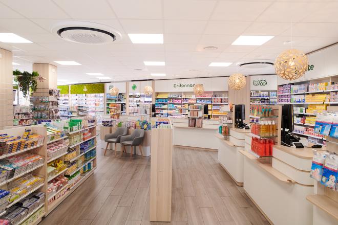 Vue d'ensemble de l'agencement d'une pharmacie moderne avec comptoirs sur-mesure en bois et sol effet parquet