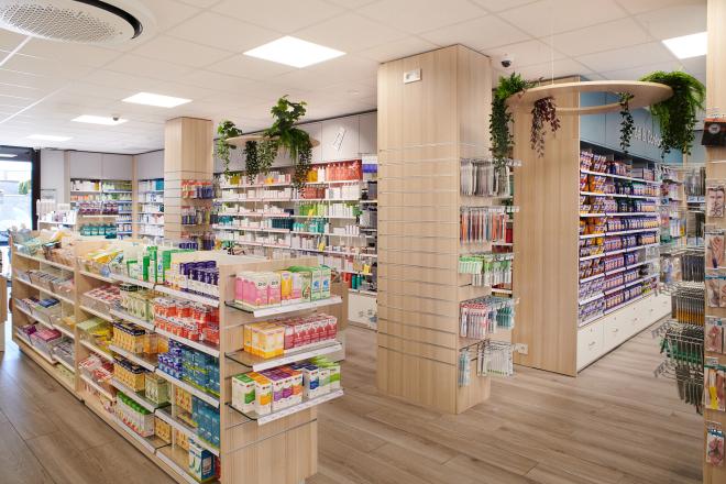 Poteaux habillés de bois avec présentoirs et décorations végétales suspendues dans une officine.