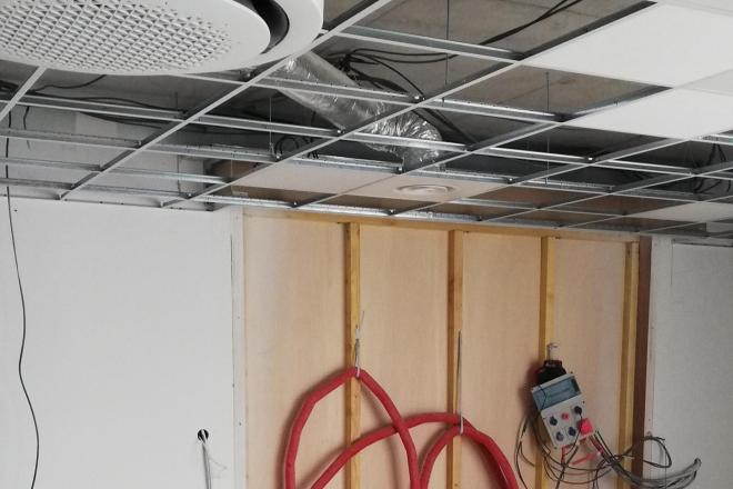 Pharmacie en cours de transfert, travaux dans local avec réseaux techniques visibles et faux plafond suspendu