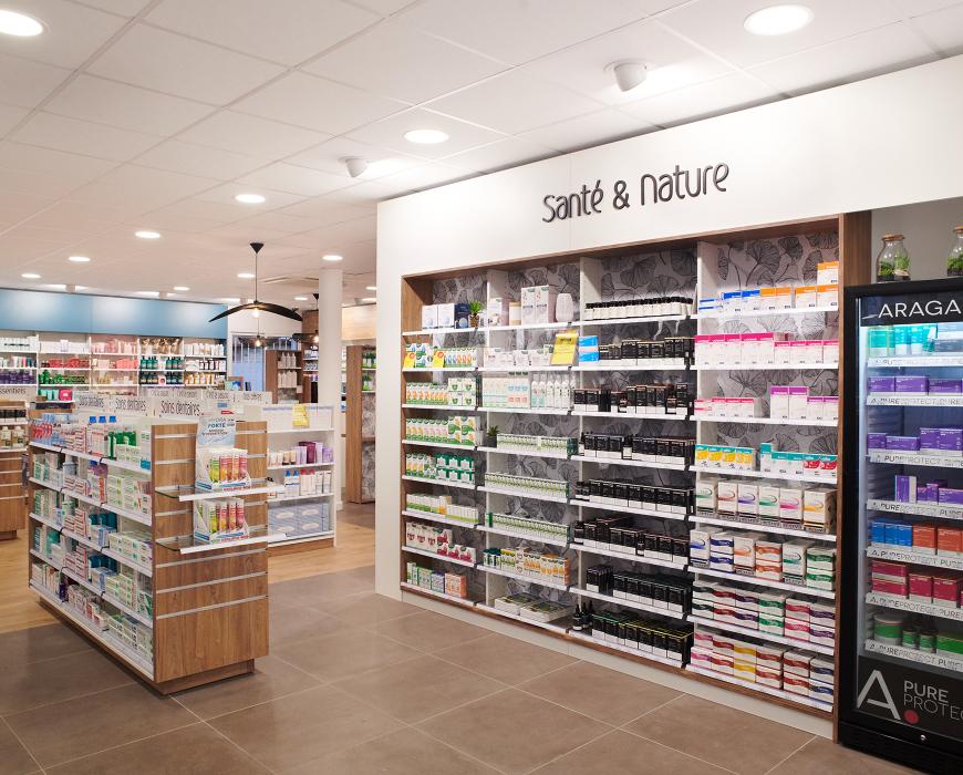 Rayon Santé et Nature de pharmacie avec mobilier en bois, frigo à médicaments vitré et large choix de produits de santé naturelle.  