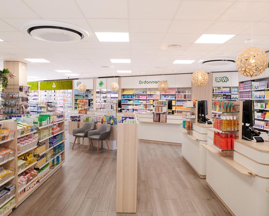 Vue d'ensemble de l'agencement d'une pharmacie moderne avec comptoirs sur-mesure en bois et sol effet parquet