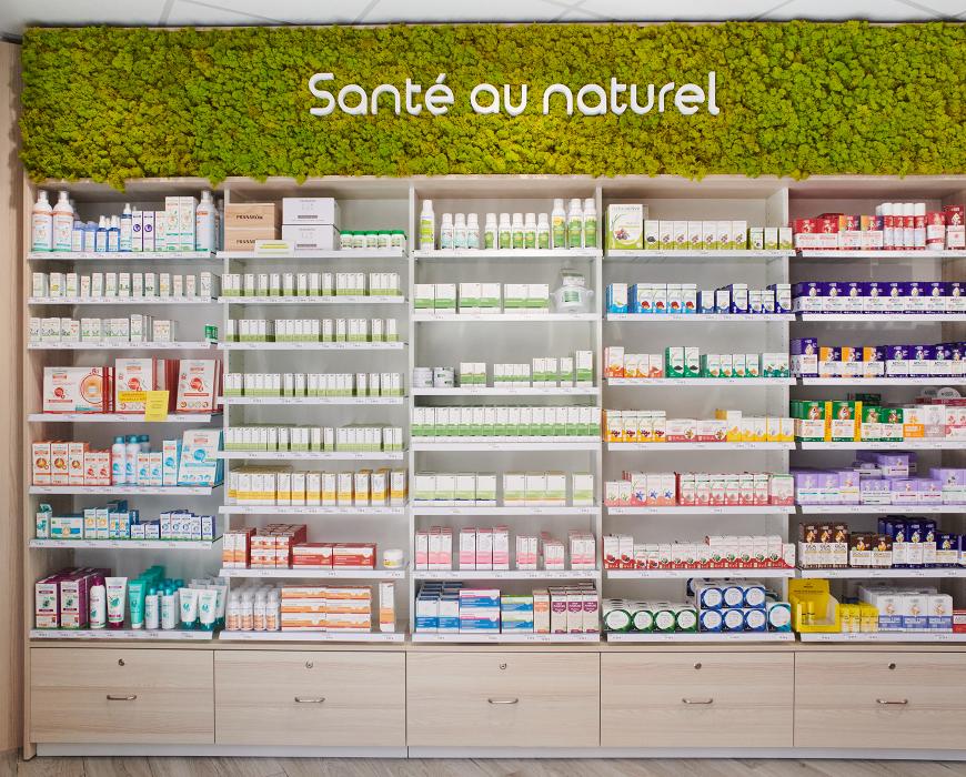 Rayonnage de pharmacie sur-mesure avec bandeau végétal « Santé au naturel » et tiroirs de rangement bas.