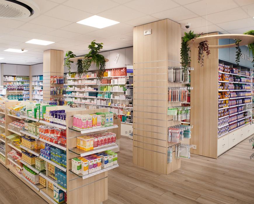 Poteaux habillés de bois avec présentoirs et décorations végétales suspendues dans une officine.