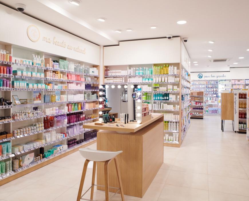 Aménagement intérieur de la pharmacie Monsieur Oliveira à Bouaye réalisé par JBCC, avec espaces de vente modernes, accueil, plots d’animation et cabines de confidentialité.