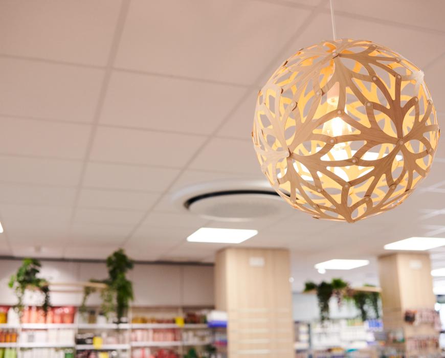 Suspension lumineuse alvéolée en bois au plafond d'une pharmacie.