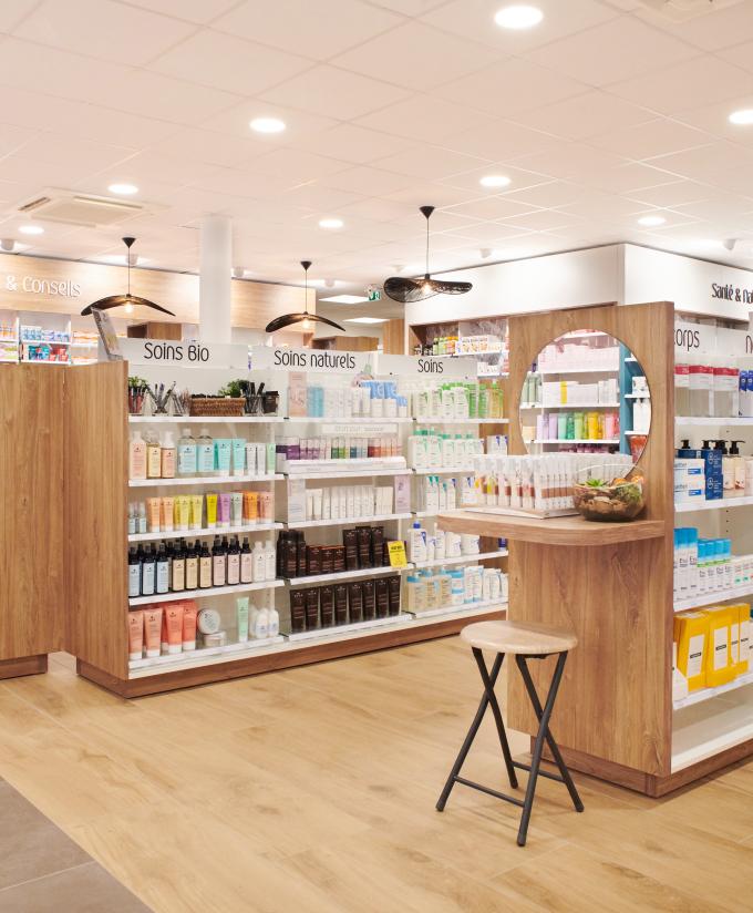 Rayonnages de parapharmacie en bois clair dédiés aux soins naturels et bio, avec gondole centrale équipée d'un miroir, agencement moderne à Machecoul.  