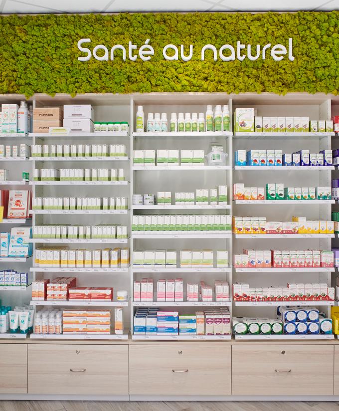 Rayonnage de pharmacie sur-mesure avec bandeau végétal « Santé au naturel » et tiroirs de rangement bas.