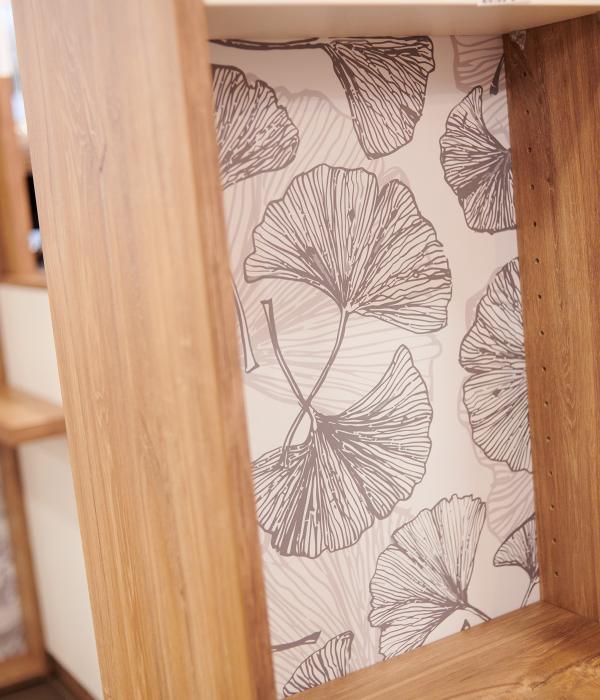 Gros plan sur les finitions d'un meuble de pharmacie JBCC avec fond de niche tapissé d'un motif botanique gris, alliance du bois et du design