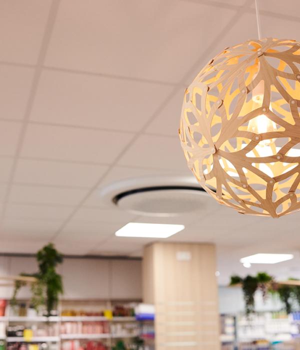 Suspension lumineuse alvéolée en bois au plafond d'une pharmacie.